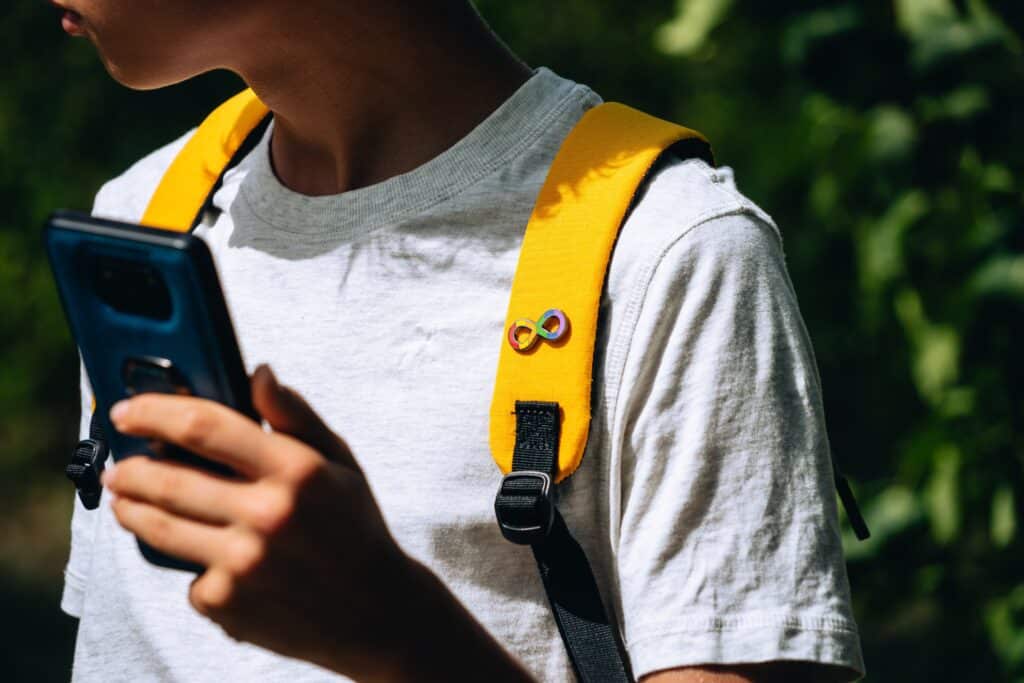 Teenage,Boy,Holding,Smartphone.,Kid,Has,Yellow,Backpack,With,Autism